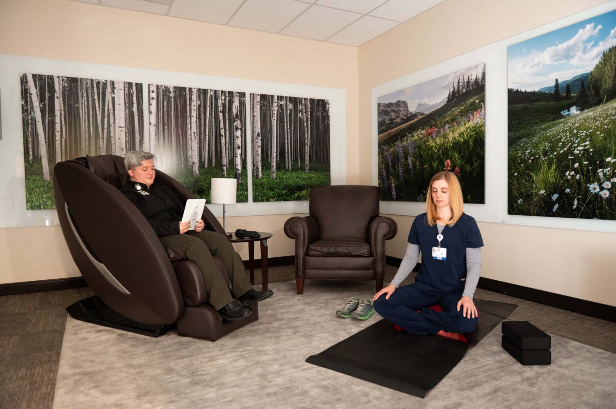 A woman peacefully seated in a massage chair, enjoying relaxation in a Zen Den while facing a captivating large picture.